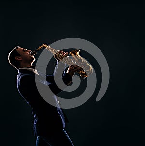 Musician plays jazz at saxophone. dark background