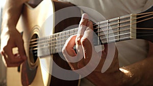 The musician plays the rhythm on a yellow acoustic guitar, pressing the strings with his fingers to the barre