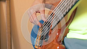 The musician plays a six-string bass guitar in his home Studio. Close up. Soft focus
