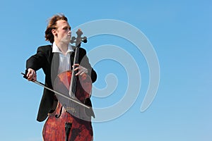 Musician plays violoncello against sky