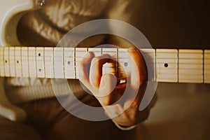 The musician plays a white electric guitar. The sound of rock music. Chords on the guitar neck