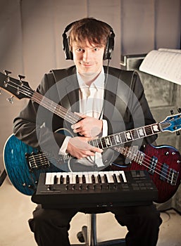 Musician portrait in studio with two guitars and keyboard