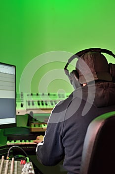 Musician, producer in headphones, working in the studio on creating and recording music. Back view of man wearing headphone