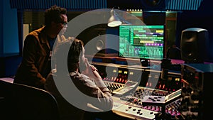 Musician and producer work on soundboard pads at professional studio