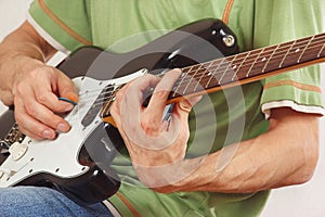 Musician put fingers for chords on electric guitar close up