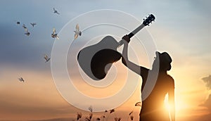 Musician raising guitar over head free birds of silhouette photo