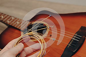 The musician replace the new guitar strings. The man's hand holding new music strings. Music theme