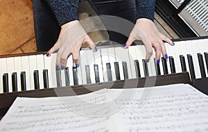 Musician`s female hands with manicure and white black piano keys while playing music
