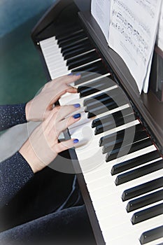 Musician`s female hands with manicure and white black piano keys while playing music