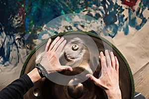 A musician& x27;s hand playing the handpan with other people.