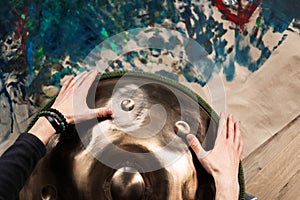 A musician& x27;s hand playing the handpan with other people.