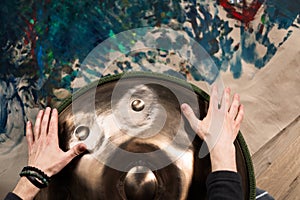 A musician& x27;s hand playing the handpan with other people.