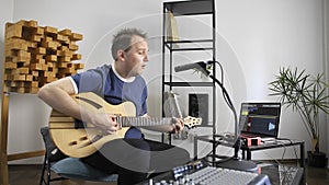 Musician singing and playing electric guitar in home music studio.