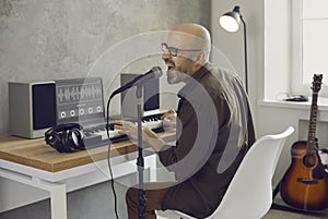 Musician singing and playing music on MIDI keyboard in his home recording studio