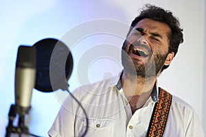 Musician singing at the top of his lungs in front of the microphone