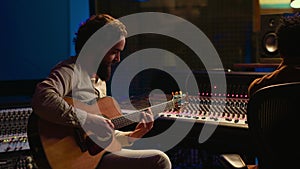 Musician and sound engineer recording guitar tunes in control room