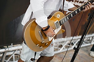 A musician on stage playing a gold colored electric guitar