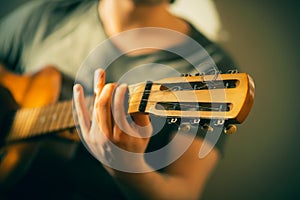 A musician in a t-shirt plays a tune on an old acoustic guitar