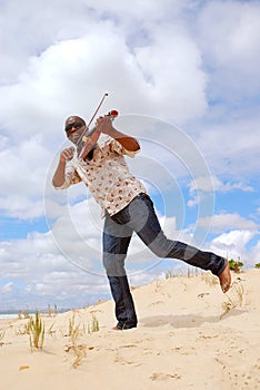 Musician with violin playing on the beach