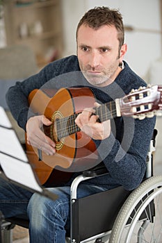 musician in wheelchair playing guitar at home