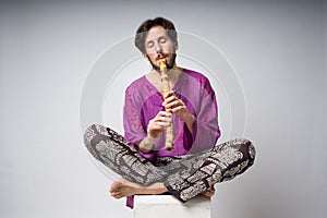 The musician who plays ethnic instruments. The man sitting in the lotus position plays the flute.
