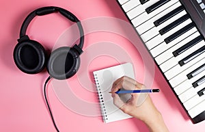 Musician is writing on notebook with studio pink
