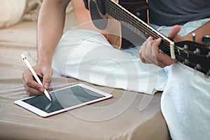 Musicians play guitar and compose songs using the tablet.
