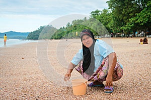 Musilim woman collecting shells on a beach.