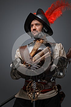 Musketeer duelist with epee looking away against gray background