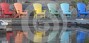 Colorful chairs in a row on the dock at the lake in summer