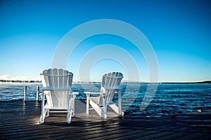 Muskoka Chairs on a dock with sun rising and mist