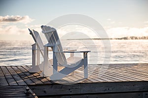 Muskoka Chairs on a dock with sun rising and mist photo