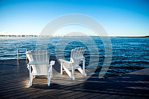Muskoka Chairs on a dock with sun rising and mist photo