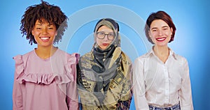 Muslim, African and European girls isolated look at the camera, internationality, blue background, friendship of nations