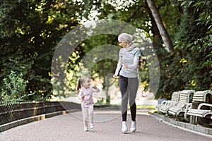 Muslim Arabian woman enjoying running together in park with her cute active 4-aged daughter