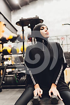 Muslim asian woman in hijab exercizing in a gym.