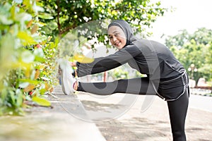 muslim asian woman strecth her leg during sport time outdoor