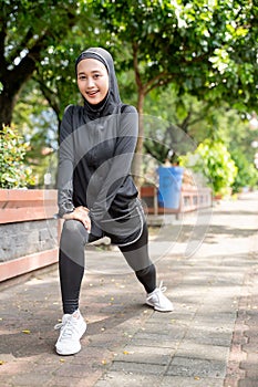 muslim asian woman strecth her leg during sport time outdoor