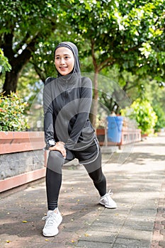 muslim asian woman strecth her leg during sport time outdoor