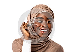 Muslim black lady applying moisturizer or hyaluronic acid on face