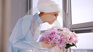 Muslim bride in blue wedding dress for nikah, smelling flowers