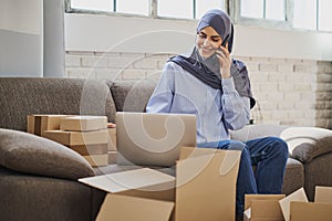 Muslim business woman having a call and looking at a laptop