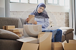 Muslim business woman talking on the phone and packaging orders from her shop
