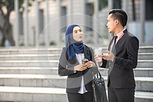 Muslim Businessman and Businesswoman having a conversation during a coffee break. Outdoor scene
