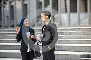 Muslim Businessman and Businesswoman having a conversation during a coffee break. Outdoor scene