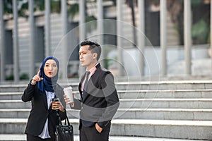 Muslim Businessman and Businesswoman having a conversation during a coffee break. Outdoor scene