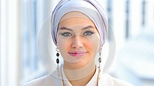 Muslim businesswoman in silver hijab looks smilingly photo