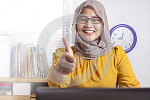 Muslim Businesswoman Working on Laptop at the Office, Smiling and Thumb Up