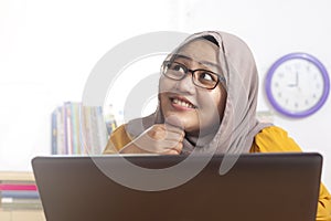 Muslim Businesswoman Working on Laptop at the Office, Thinking Gesture