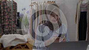 muslim businesswomen using mobile phone working in her workshop
